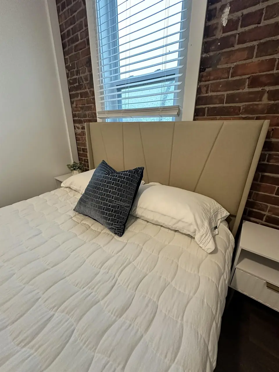 Bedroom with exposed brick wall and upholstered bed